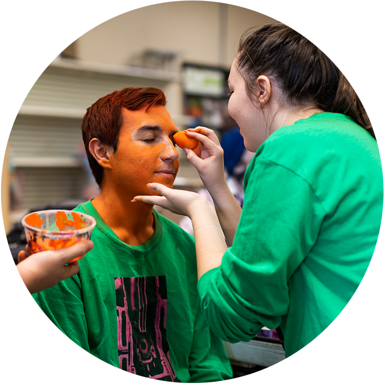 A make-up artist putting orange paint on someone's face