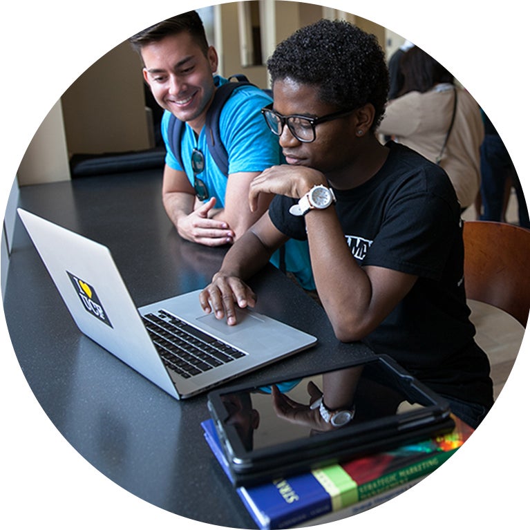 Two students sitting at a table working on a laptop