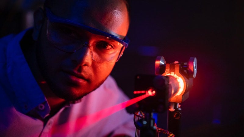 Man with safety glasses examining laser