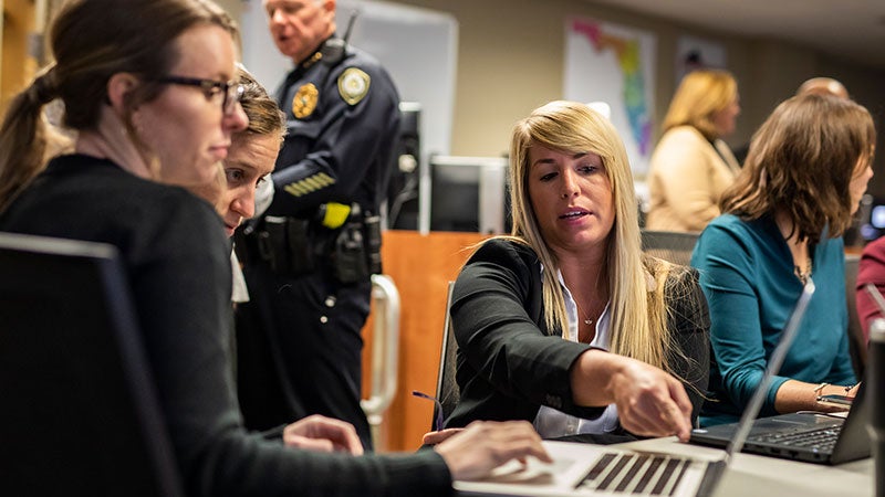 employees collaborating around a laptop during an emergency