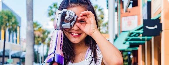 Young girl looking through hand binoculars, her right arm being a prosthetic made by Limbitless solutions