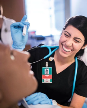 A UCF College of Nursing student works with a manikin while faculty oversee her