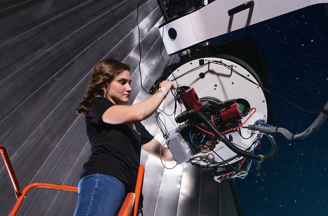 A UCF student works on a complex apparatus in Robinson Observatory on the main campus.