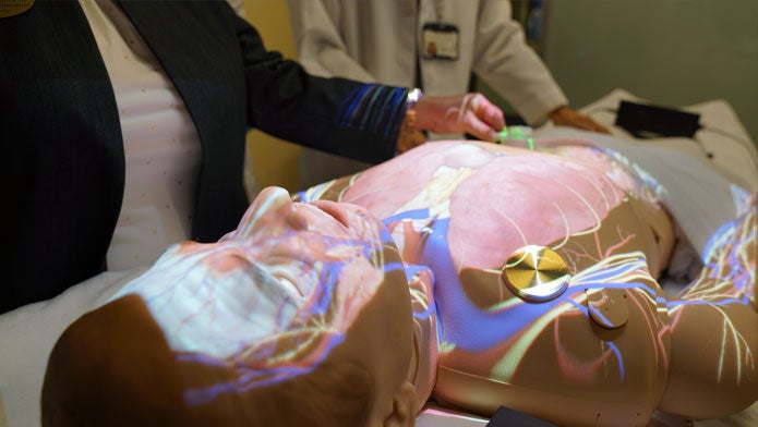 Students work up close with a medical manikin