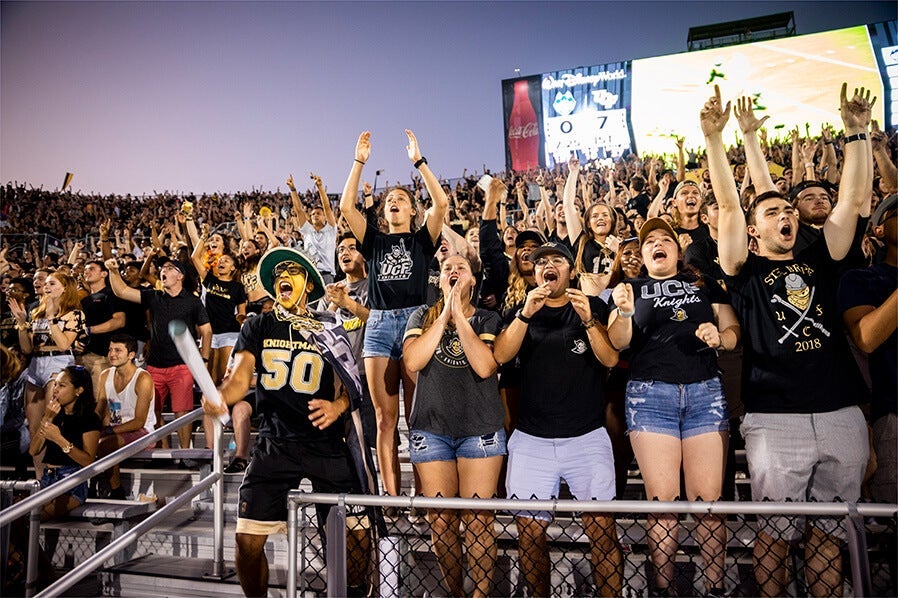 Students cheering the UCF Knights at a campus football game