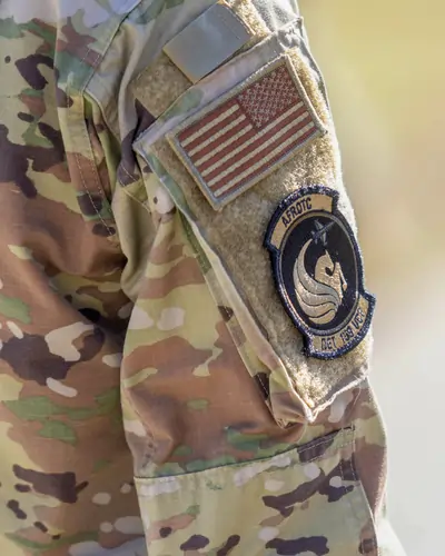 Close-up of a camouflage sleeve with an embroidered U.S. flag and UCF ROTC Pegasus patch, highlighting support for student veterans and military.