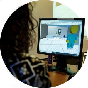 Person viewing a 3D hospital room simulation on a computer monitor.