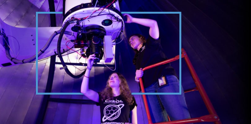 Two UCF researchers working on a telescope