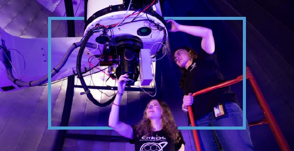 Two UCF researchers working on a telescope