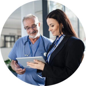 Healthcare professional and businesswoman reviewing a tablet together.