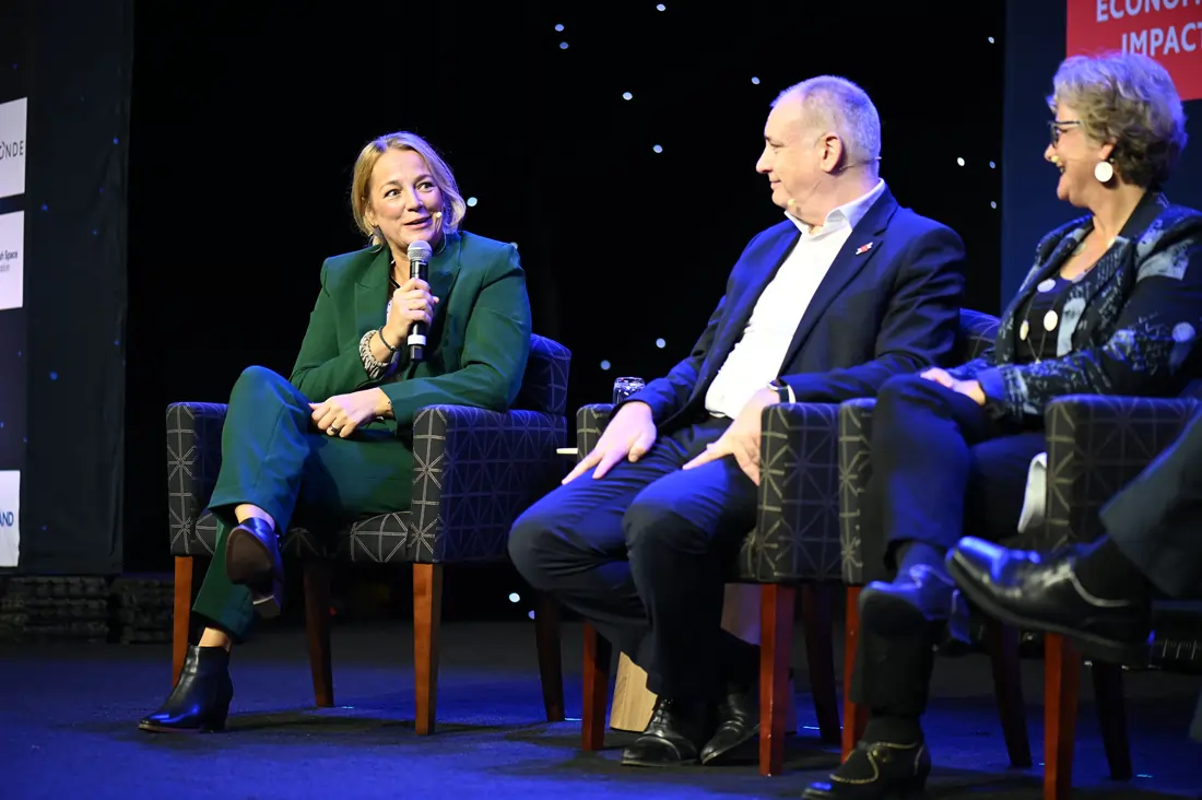 Three speakers seated together on stage in conversation during a panel discussion at the Economist Space Economy Summit in 2025.