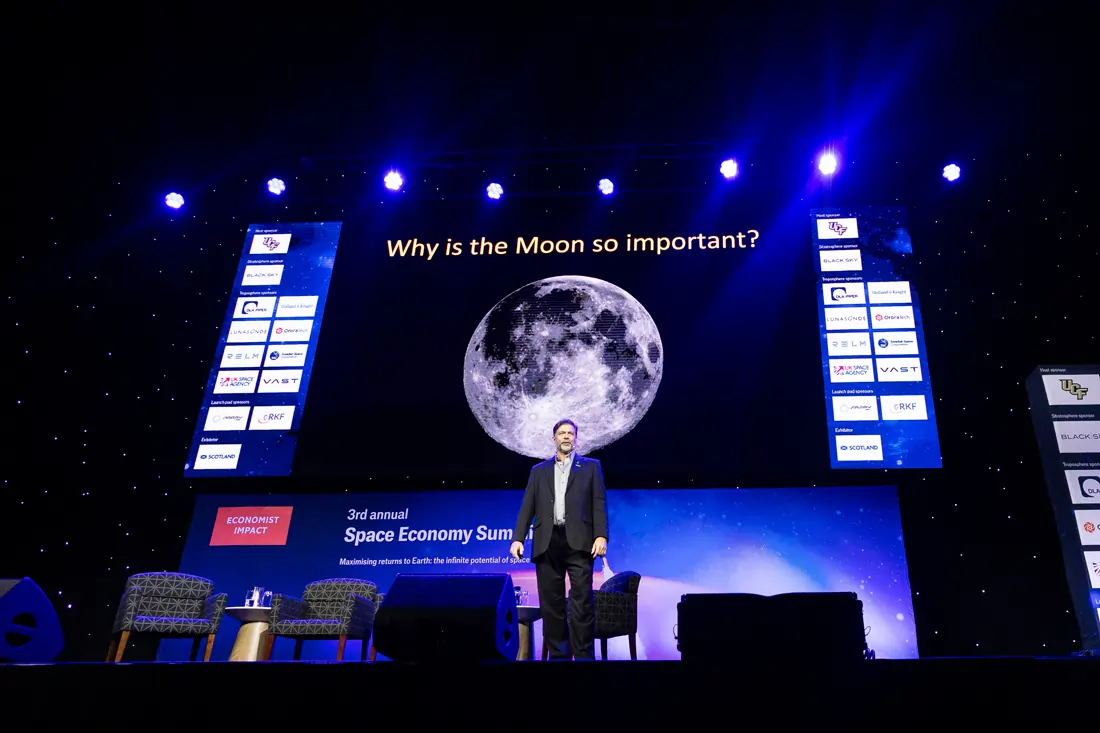 Phil Metzger delivering the closing keynote in front of a large moon graphic and the question Why is the Moon so important?