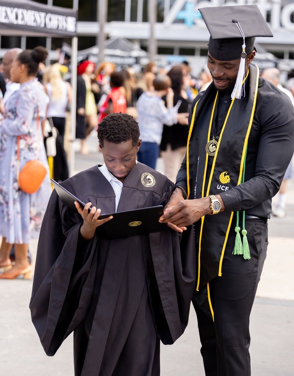 A graduate in cap and gown is embraced by family after Commencement.