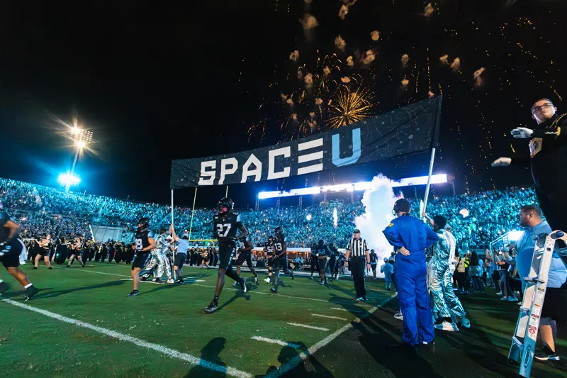 UCF football players run onto the field during the Space Game.