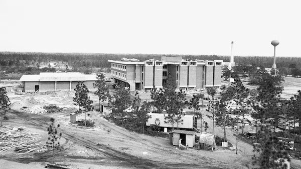1968 black and white aerial view of UCF's Chemistry Building under construction, surrounded by dirt, scattered trees, and a water tower in the distance.