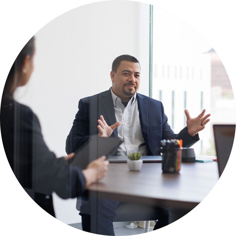 Business professional speaking during a meeting at a conference table.