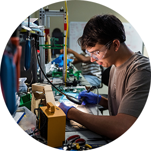 Electrical engineer solders electronic components at a laboratory workbench.
