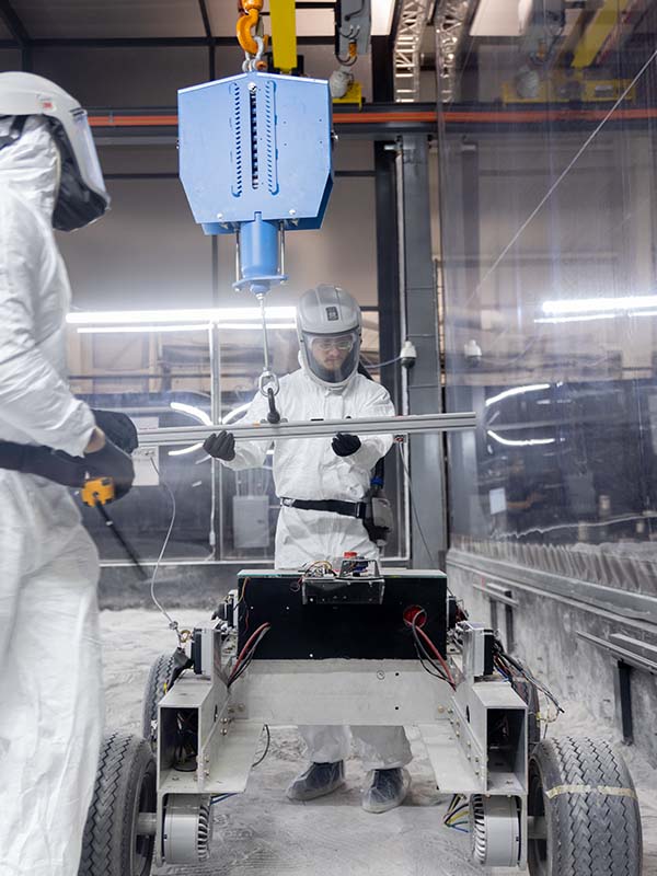 Two researchers test a robotic rover in a simulated lunar environment.