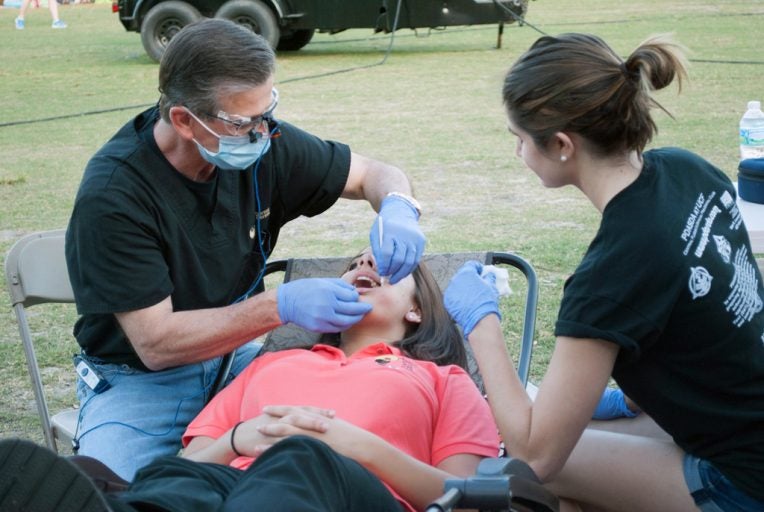 Health Services Dentist screening a participant for oral cancer.