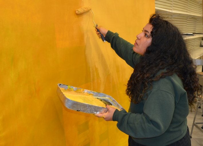 Adryanna Rivera-Delgado, a senior studio art major, works on the early stages of recreating a Gustav Klimt painting for the tableau vivant exhibit.