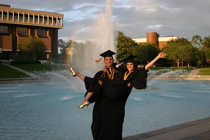 Will+Jessica graduation photo: standing in front of the reflecting pond, will is holding jessica in his arms