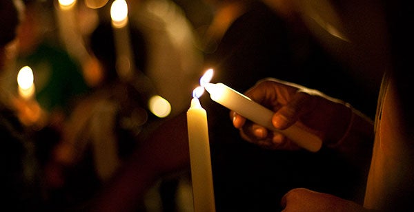 person lighting a candle from another candle's flame at a candlelight vigil for pulse victims