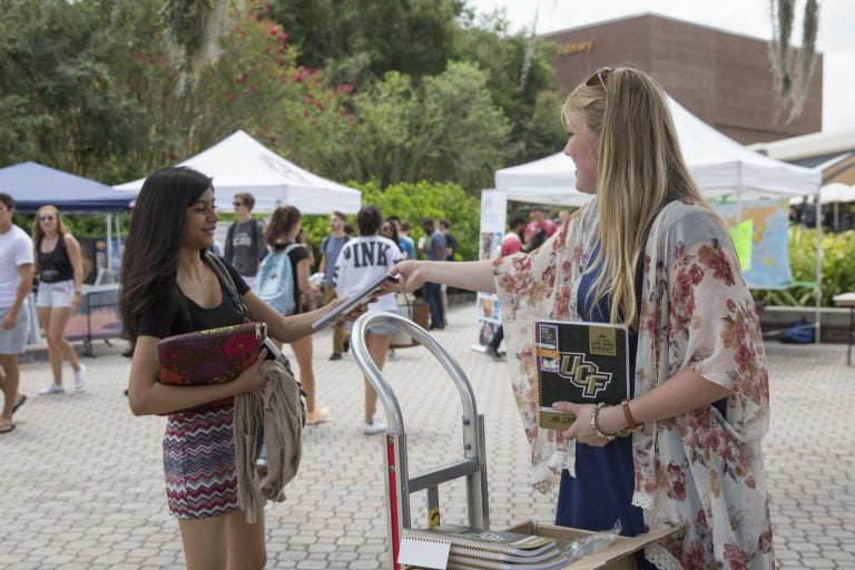 woman handing student pamphlets by the student union