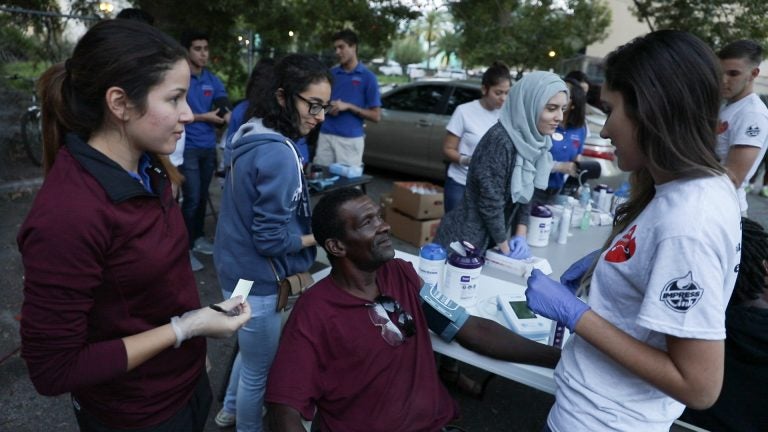 UCF student-volunteers with Hearts for the Homeless Orlando measure blood pressure and provide health information to John Driffin.