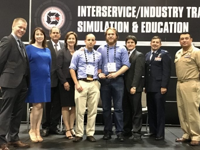 Zackary Henderson and Tyler Quillen (center) accepting the Best Serious Game Innovation award.