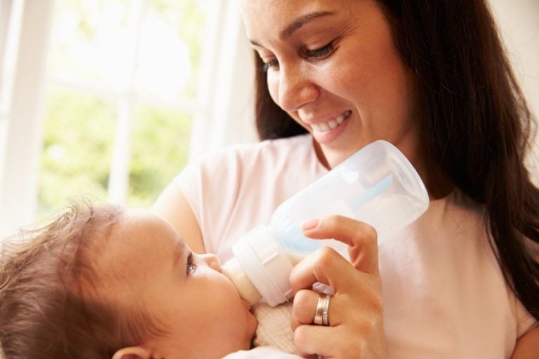 Mother Feeding Baby Boy From Bottle At Home