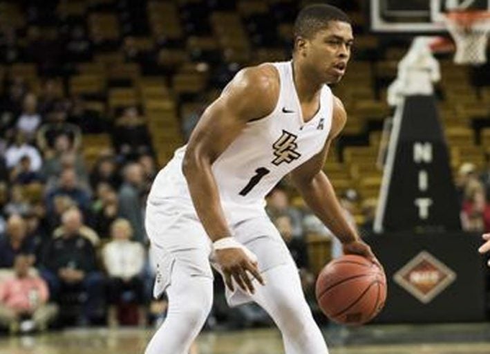 ucf basketball player in white uniform dribbling ball during game