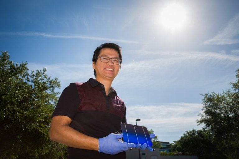 UCF Solar Expert, man holding solar cells outside with sun beaming down