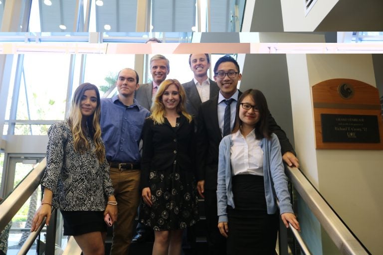 group of men and women dressed up. photo taken from a low angle while they stand at the top of the stairs