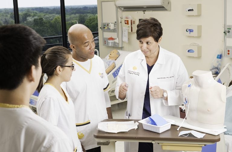 Laura Gonzalez, PhD, ARNP, CNE, CHSE, with students in the nursing skills lab