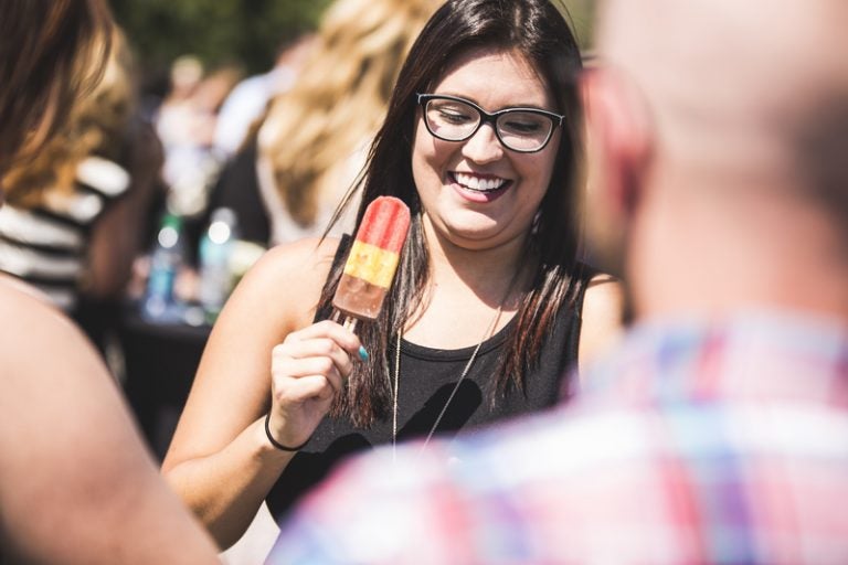 woman holding red popsicle in large crowd of people