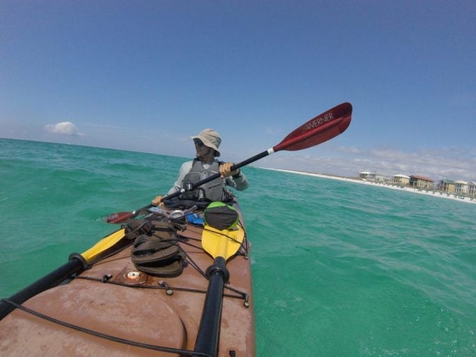 ucf student paddling in kayak in beautiful blue/green ocean