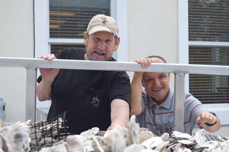 two men smiling behind fence