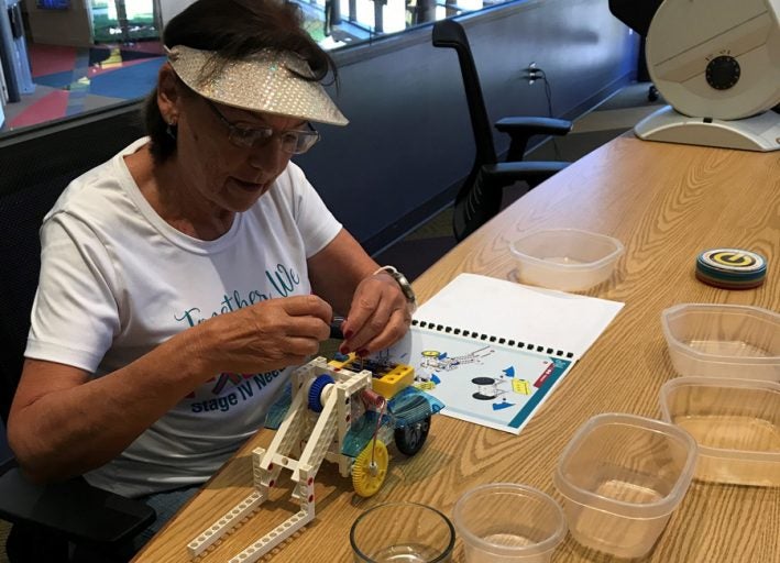 Volunteer Kathleen Sanborn assembles a robot kit using easier-to-understand picture instructions.
