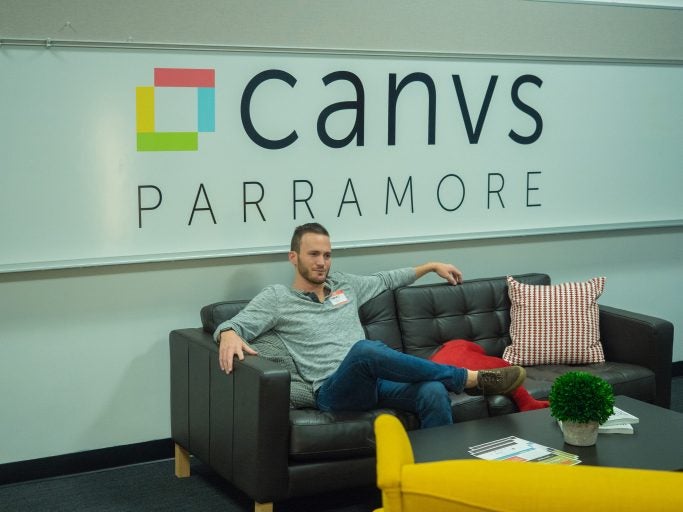 man sitting on couch in front of banner that reads "canvas PARRAMORE"