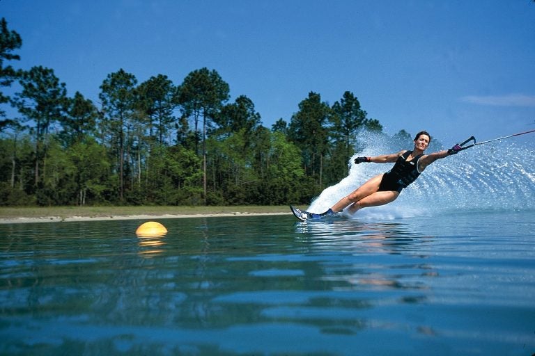 woman water skiing on still blue water