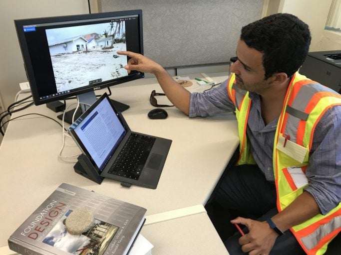 man in orange safety vest pointing at computer screen