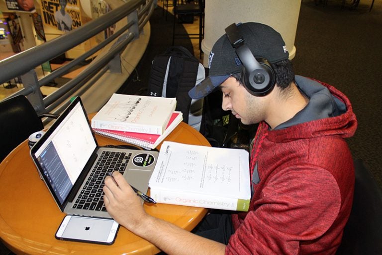 student with headphones on studying at student union table