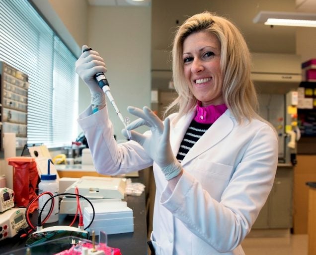 ana carr in white lab coat, smiling. staying at ucf to continue finding cancer cure.