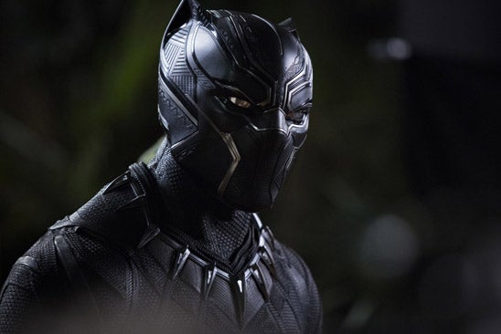 A man wears black costume that looks like a panther with claws around his neck.
