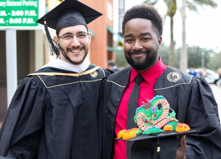 Two FIEA students in cap and gown at graduation