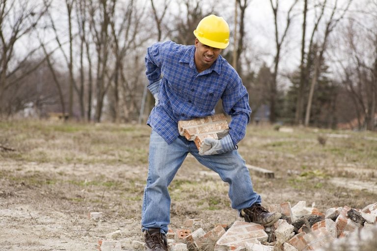 A man working on a construction site who has hurt his back. T