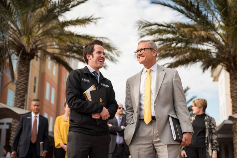 Dale Whittaker (right) speaks with Tyler Schwaegler, coordinator for residence life and education, during a tour of the UCF campus. (Photo by Nick Leyva '15)