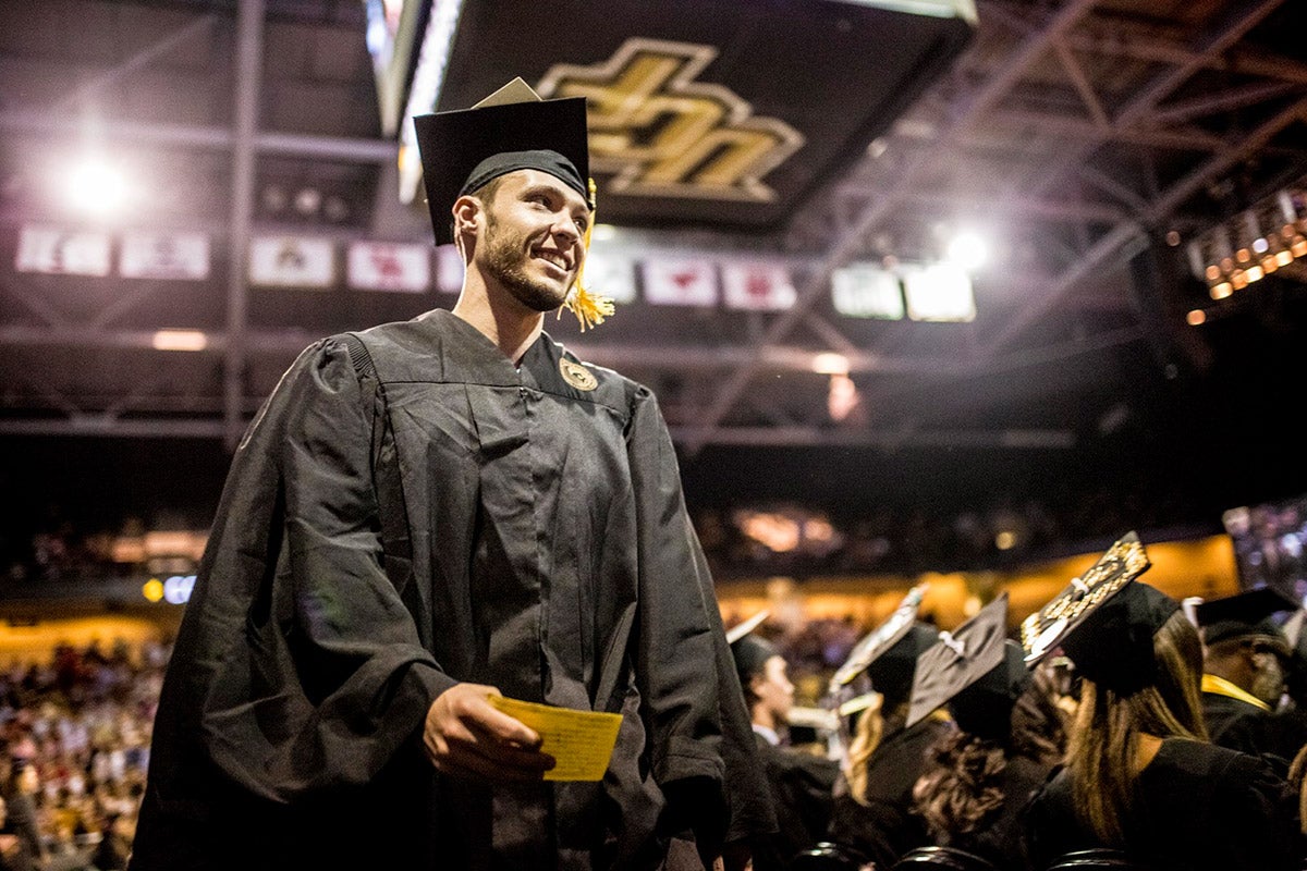 male ucf student in black cap and gown at graduation