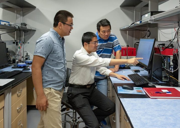 3 men in lab looking at a computer screen