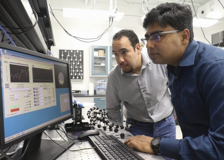 two men in a lab looking at computer screen, working on nanostructured optical sensor